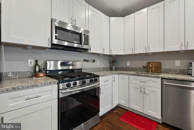 a kitchen with stainless steel appliances white cabinets a stove a microwave and a hard wood floors