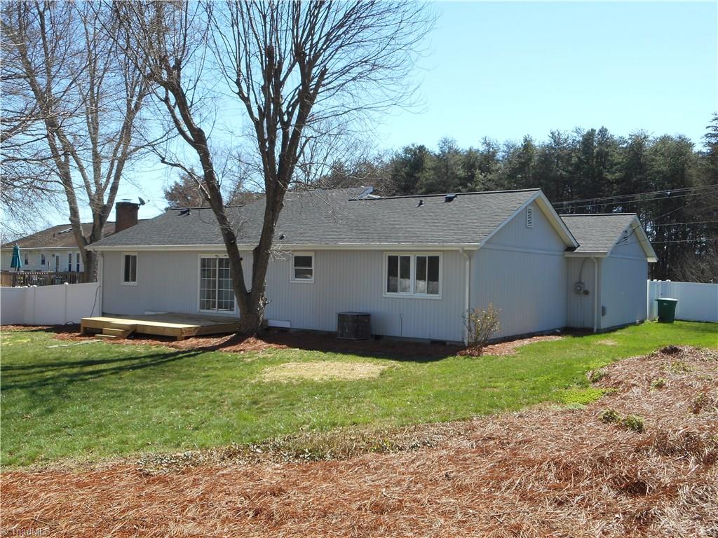 5929 Styers Ferry Road Clemmons, NC 27012 - Photo 13 of 28 In this left rear view of the home we can see how the side yard is fenced in, the pine straw landscaping and one of the mature trees.