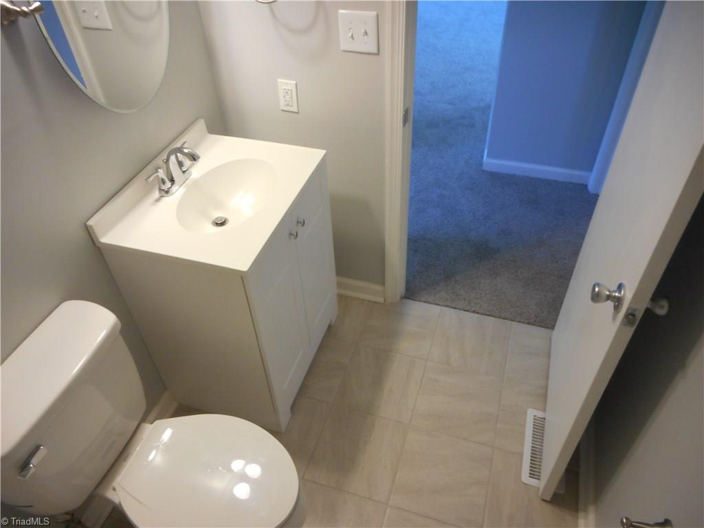 5929 Styers Ferry Road Clemmons, NC 27012 - Photo 24 of 28 In this view we are in the main hall bathroom looking out toward the main hallway from the tub side. We have the new vanity with fixtures, fresh new paint and tile flooring for easy cleaning.