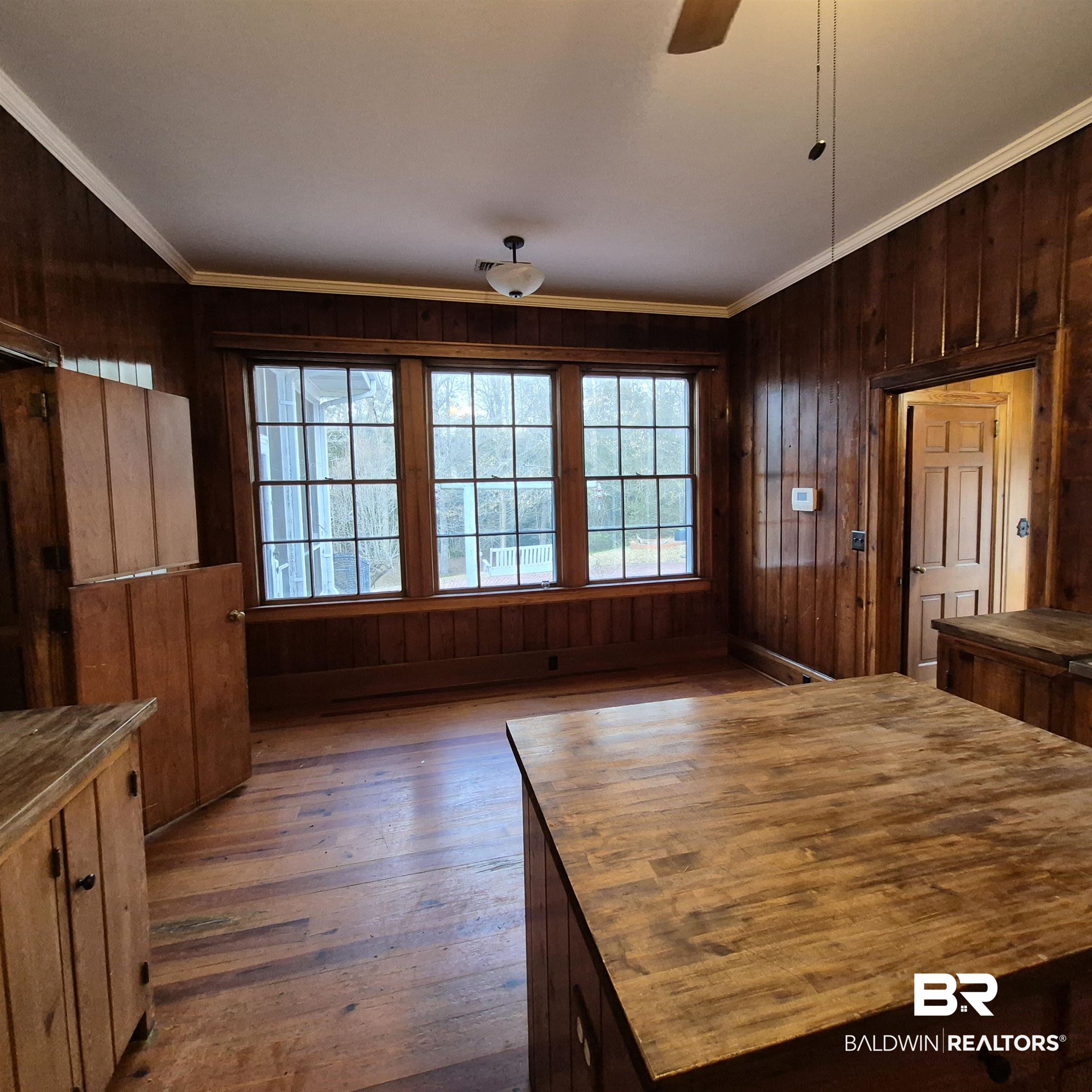 308 Rural Street Evergreen, AL 36401 - Photo 21 of 40 Unfurnished dining area with wood walls, dark wood-type flooring, a ceiling fan, and ornamental molding