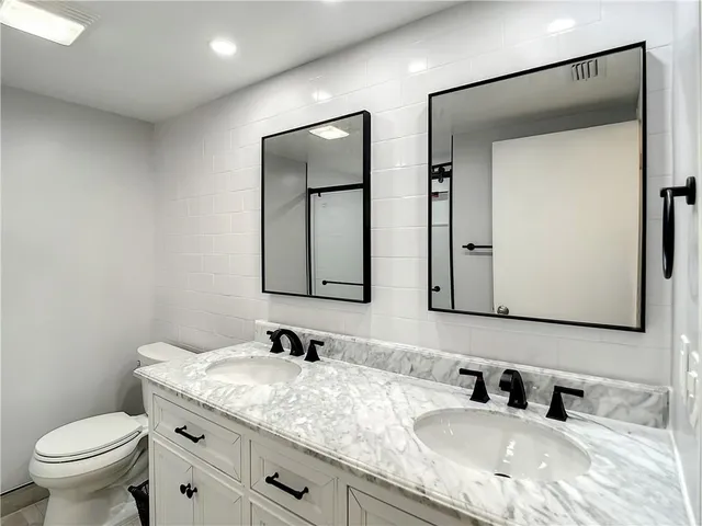 a bathroom with a granite countertop sink a toilet and mirror