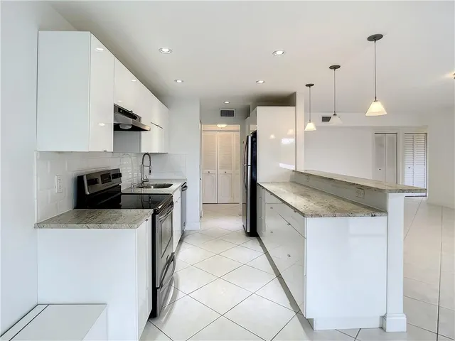 a kitchen with a sink a counter top space stainless steel appliances and cabinets