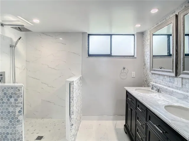 a bathroom with a granite countertop sink a mirror and shower