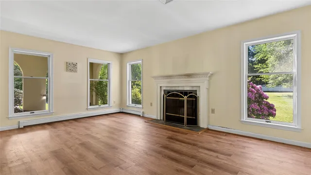 an empty room with windows and fireplace