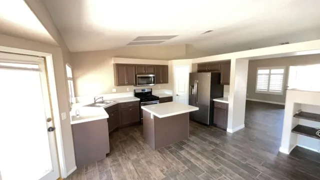 a living room with stainless steel appliances a dining table wooden floor and a window