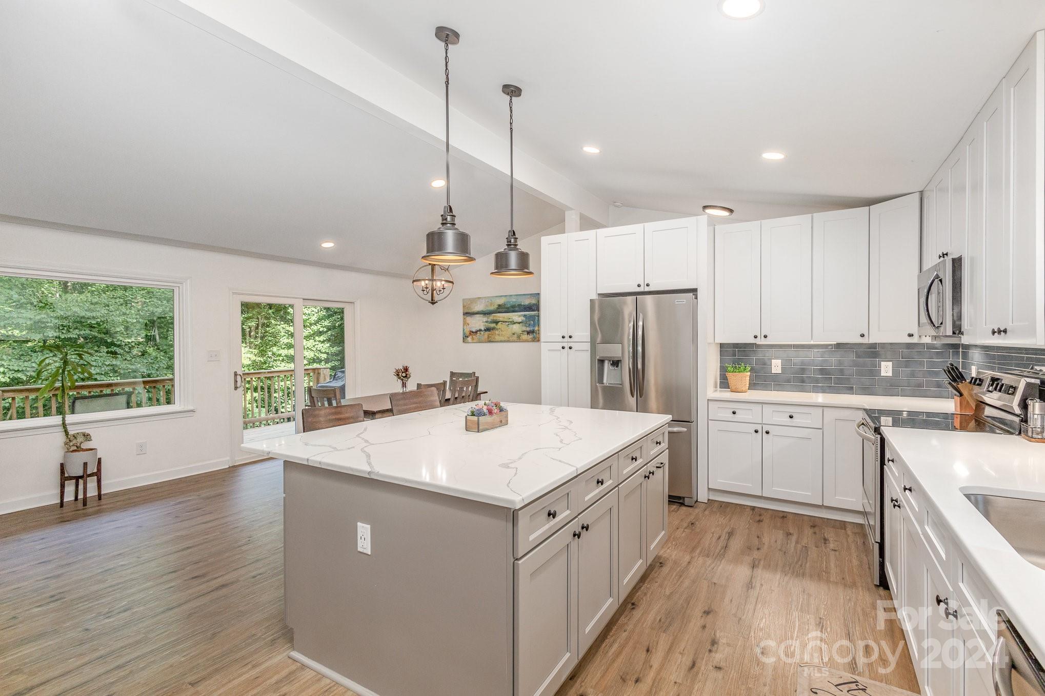 10625 East Lake Road Charlotte, NC 28215 - Photo 12 of 44 a kitchen with a sink a stove a refrigerator and white cabinets with wooden floor