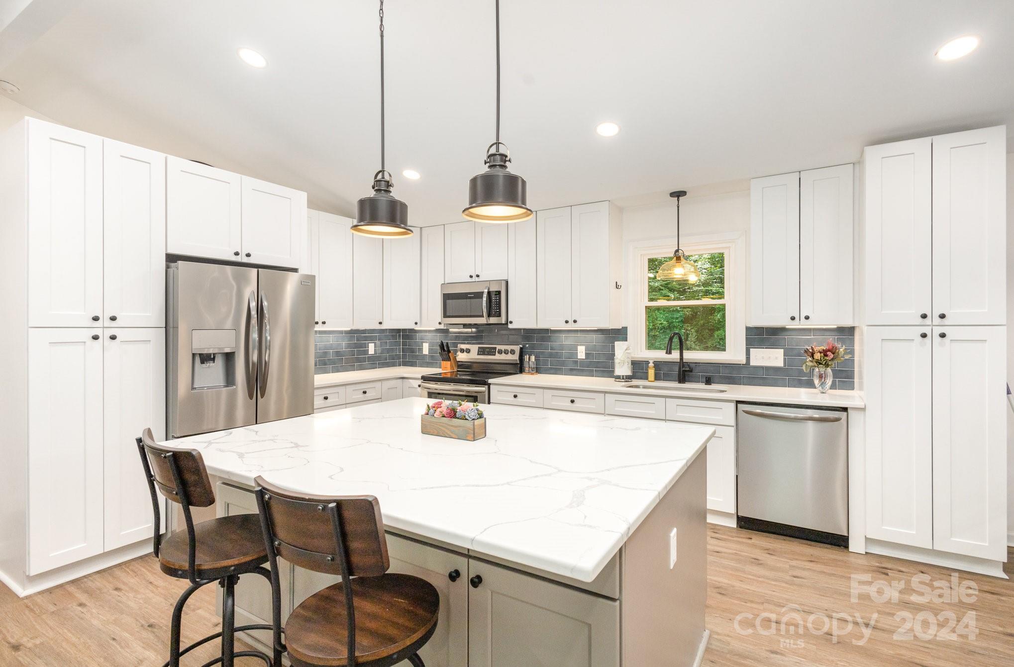 10625 East Lake Road Charlotte, NC 28215 - Photo 14 of 44 a kitchen with stainless steel appliances a dining table chairs stove refrigerator and cabinets