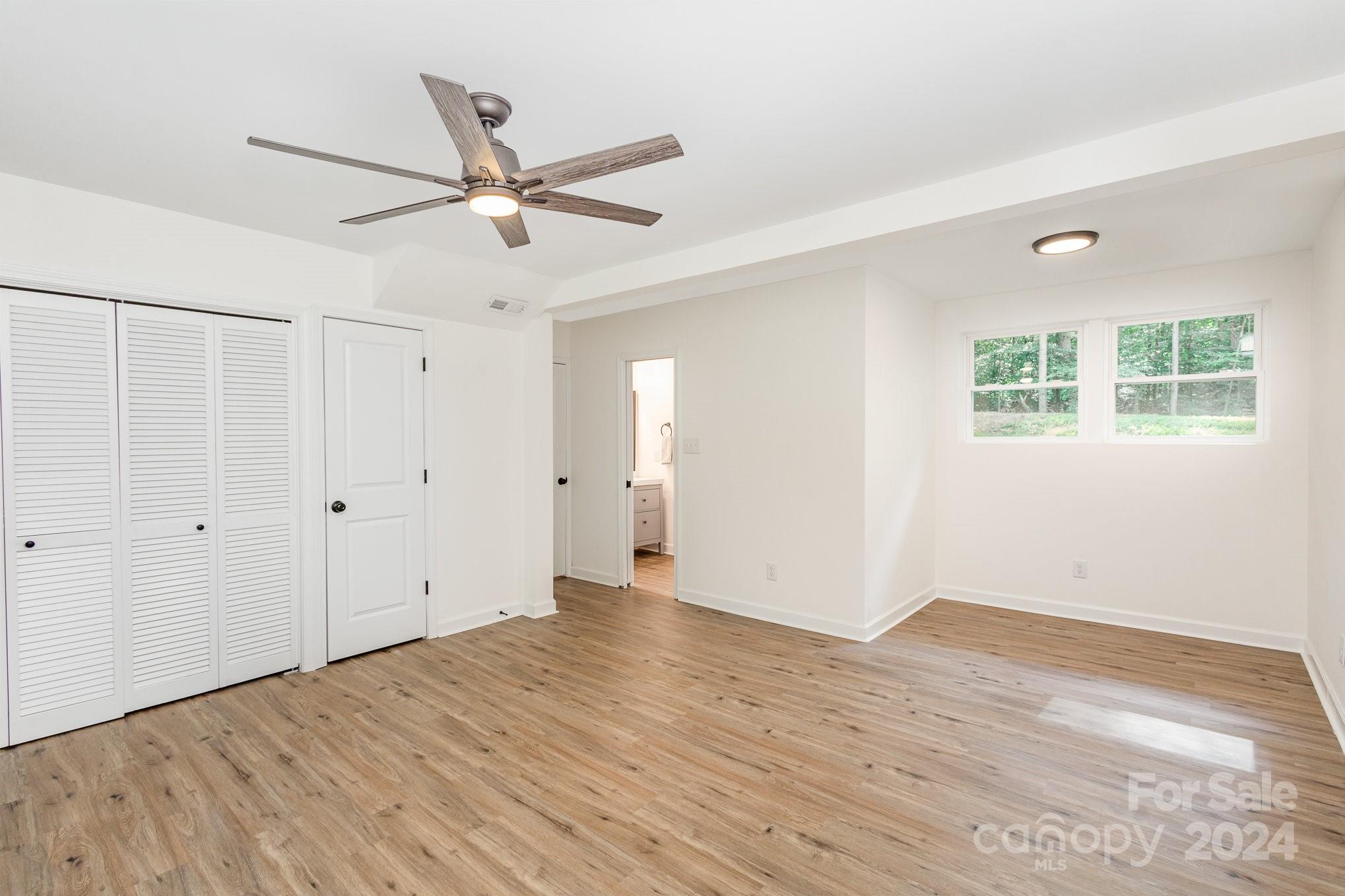10625 East Lake Road Charlotte, NC 28215 - Photo 30 of 44 an empty room with wooden floor ceiling fan and windows