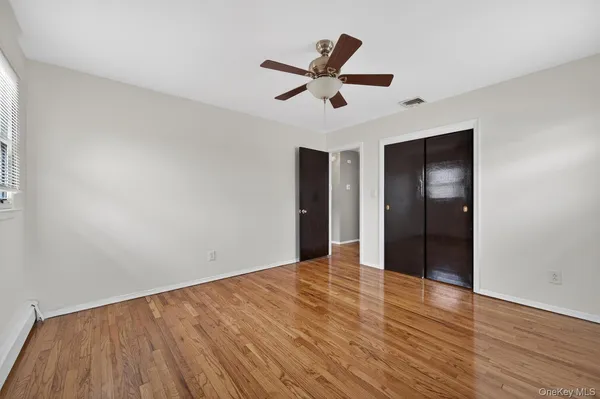 a view of empty room with wooden floor and ceiling fan