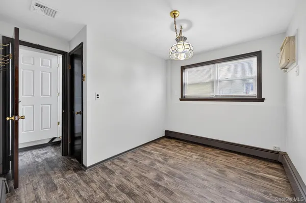 an empty room with wooden floor chandelier and windows