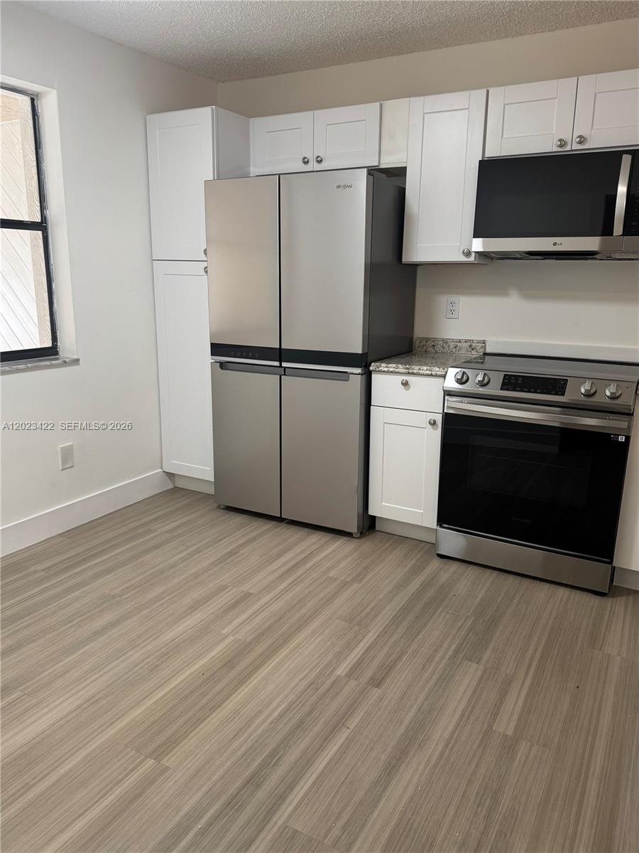 605 Ives Dairy Road, Unit 3067 Miami, FL 33179 - Photo 8 of 28 a kitchen with a refrigerator stove and wooden cabinets