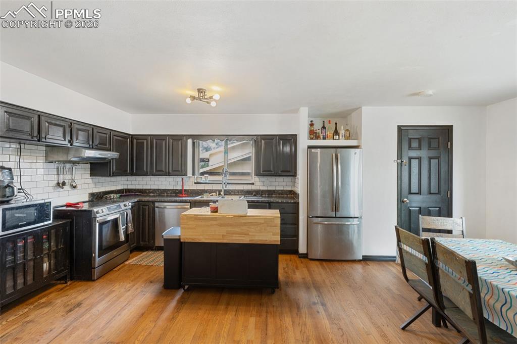 336 Harvard Street Colorado Springs, CO 80911 - Photo 9 of 27 a large kitchen with stainless steel appliances granite countertop a stove a refrigerator a sink dishwasher and a stove with wooden floors