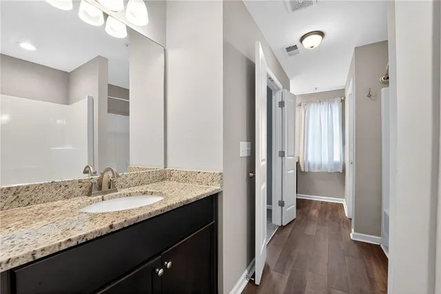 a en suite bathroom with a granite countertop sink a mirror and a shower