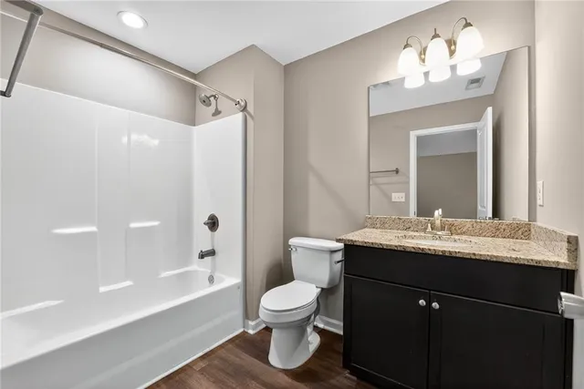 a bathroom with a granite countertop sink toilet a large mirror a bathtub and shower