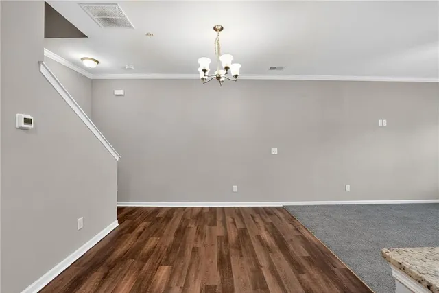 a view of an empty room with chandelier fan and wooden floor
