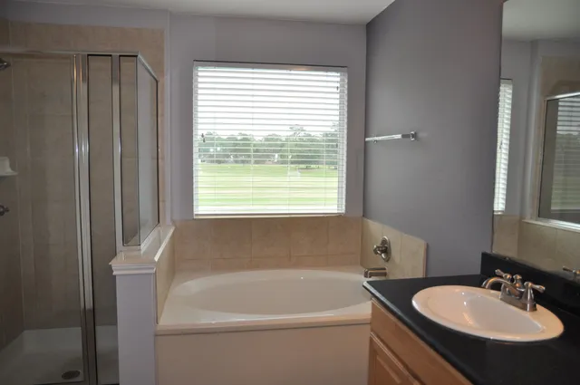 a bathroom with a sink a bathtub and next to a window
