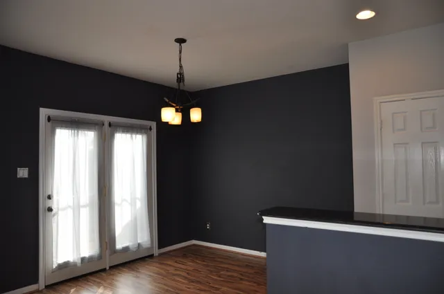 a view of a hallway with wooden floor and a chandelier