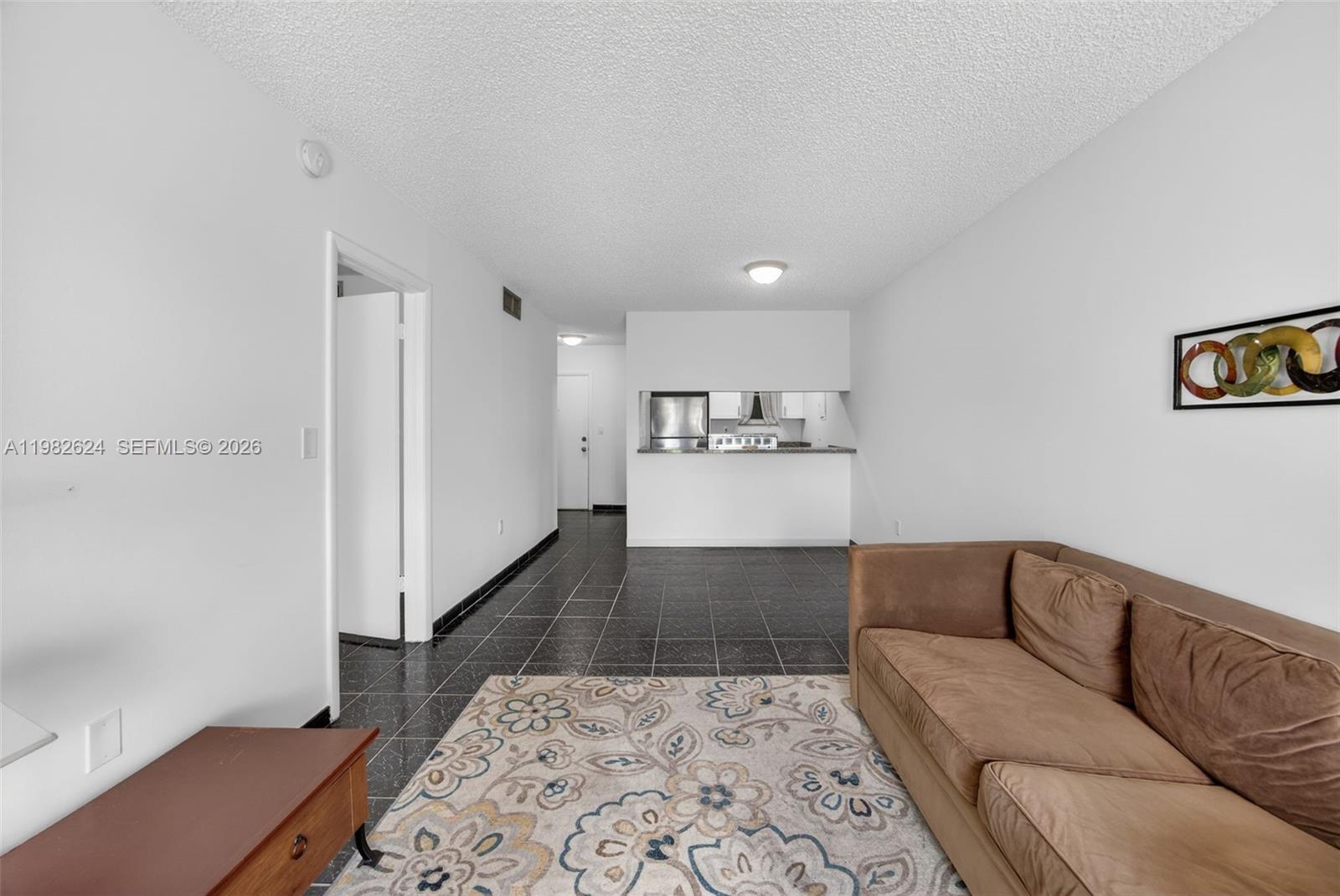 3181 Southwest 13th Street, Unit 416 Miami, FL 33145 - Photo 2 of 40 a living room with a couch and a dresser with wooden floor