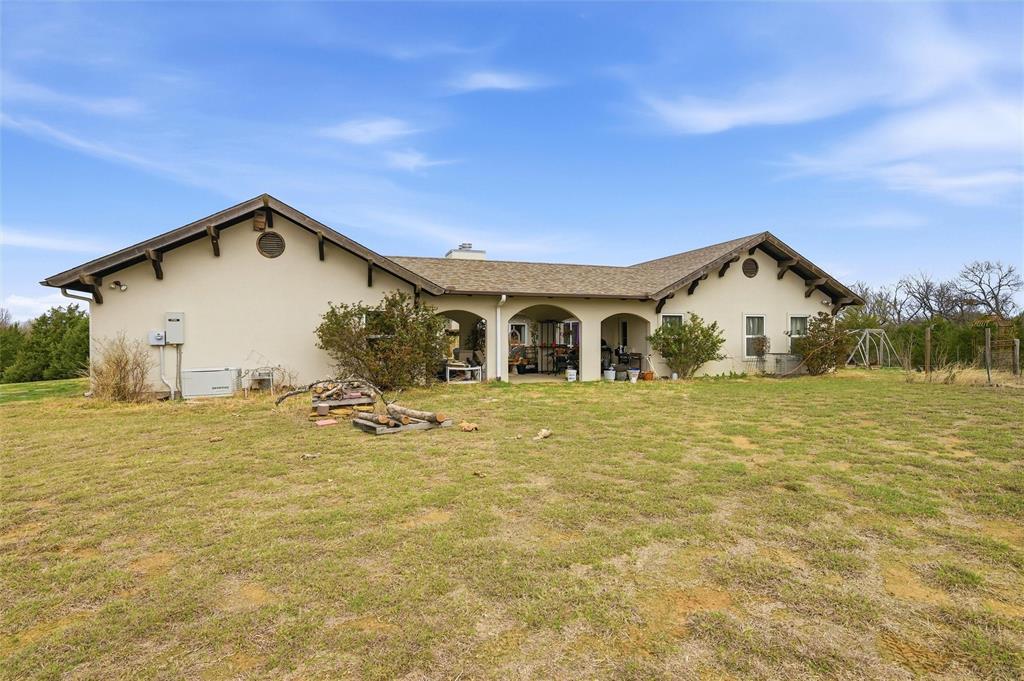 1959 Marlow Road Bells, TX 75414 - Photo 20 of 33 Back of house with a yard, stucco siding, a patio, and a chimney