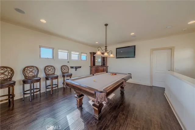 a room with furniture pool table wooden floor and windows