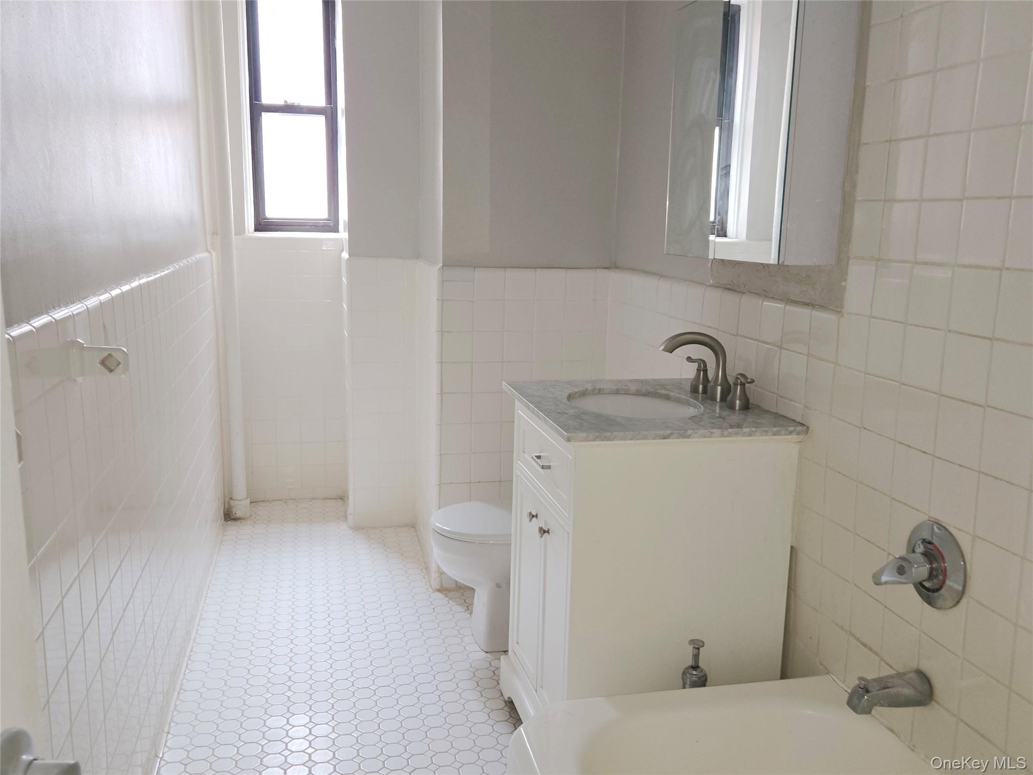 55 East 190th Street, Unit 45 Bronx, NY 10468 - Photo 10 of 13 Bathroom with tile walls, vanity, a wainscoted wall, and light tile patterned floors