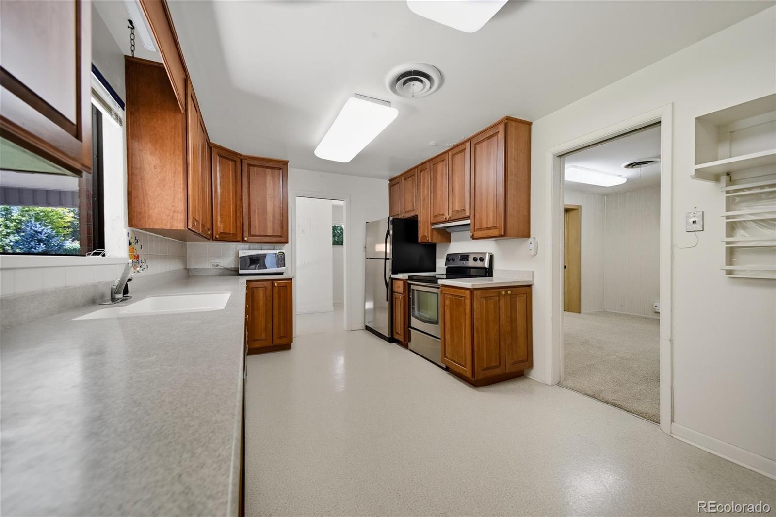 101 Hudson Street Denver, CO 80220 - Photo 9 of 27 a kitchen with stainless steel appliances granite countertop a stove top oven a sink a refrigerator and white cabinets with wooden floor