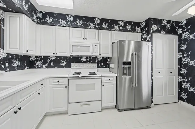 a kitchen with white cabinets and refrigerator
