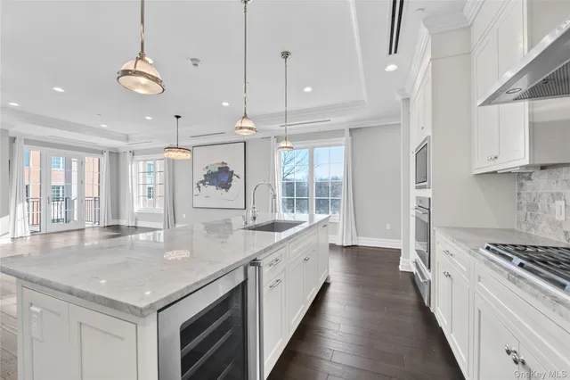 a large kitchen with stainless steel appliances kitchen island granite countertop a large center island a stove a refrigerator cabinets and living room view