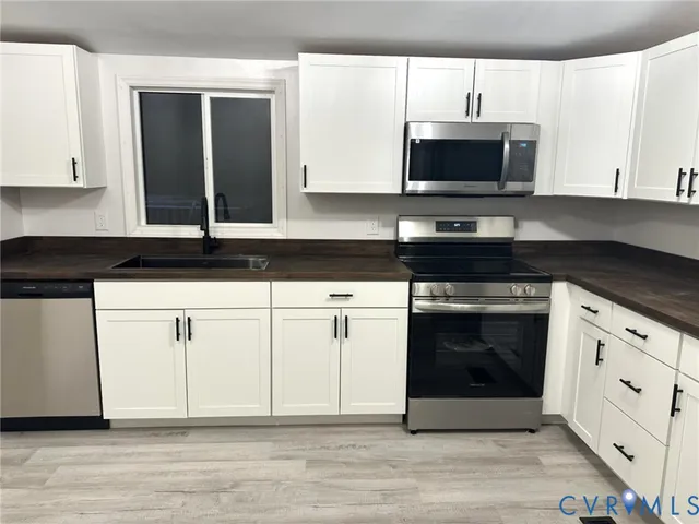 a kitchen with white cabinets and black appliances