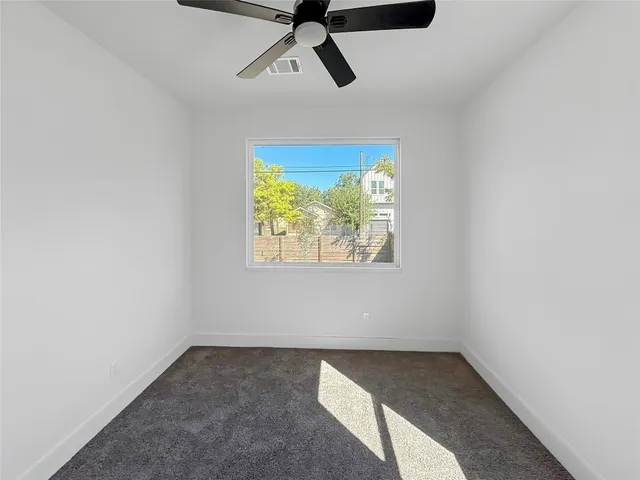 an empty room with a ceiling fan and a window