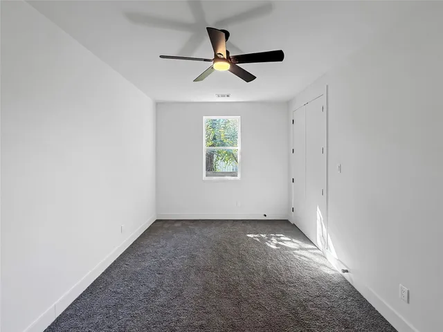 an empty room with windows and ceiling fan