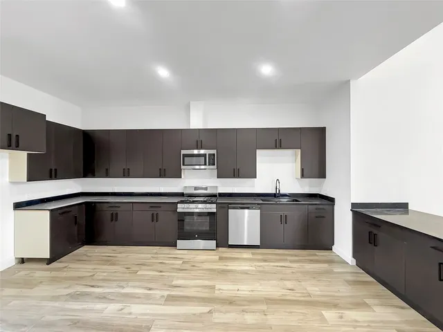 a large kitchen with stainless steel appliances granite countertop a stove and a sink