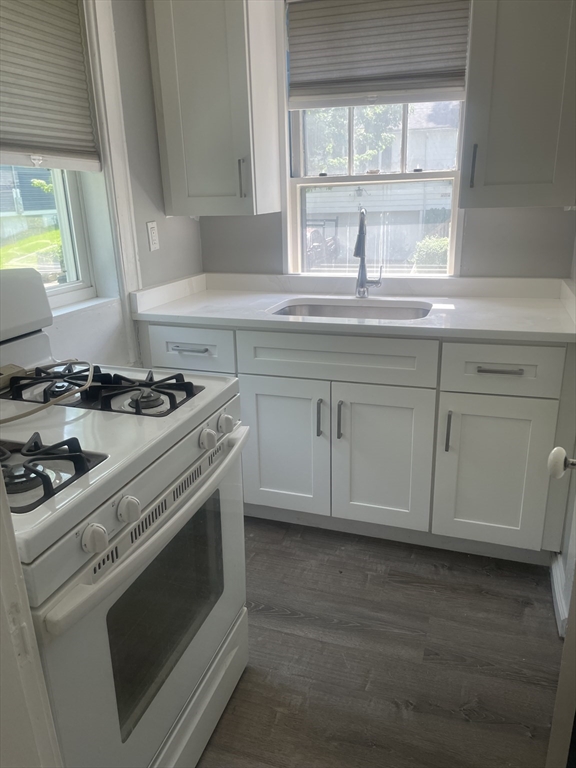 21 Arbor Lane, Unit 21 Dedham, MA 02026 - Photo 4 of 10 a kitchen with granite countertop white cabinets appliances a sink and a window