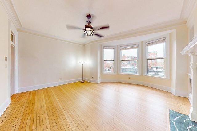 an empty room with wooden floor fan and windows
