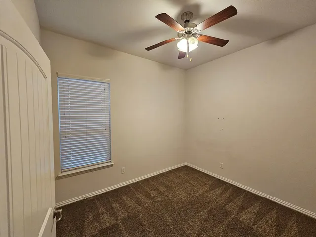 an empty room with a chandelier fan and windows