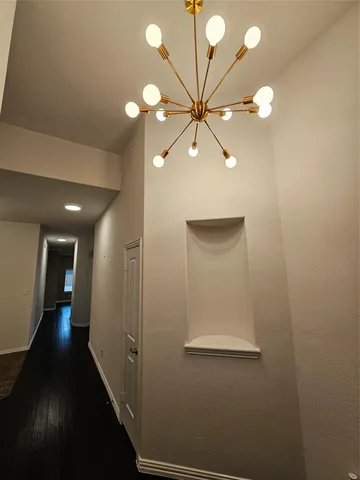 a view of a hallway with a chandelier fan and wooden floor