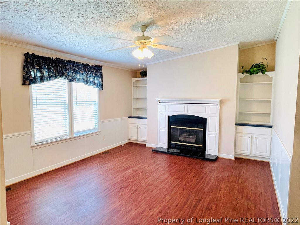 4684 East Raynham Road Fairmont, NC 28340 - Photo 10 of 26 an empty room with windows a fireplace and wooden floor