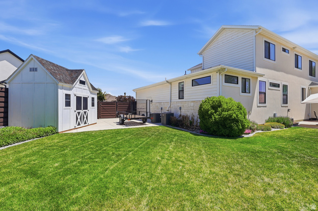 10676 Urban Rdg Cove South Jordan, UT 84095 - Photo 47 of 48 Manicured lawn with a detached storage shed, concrete patio, and mature landscaping