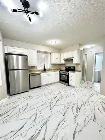 a large kitchen with white cabinets and stainless steel appliances