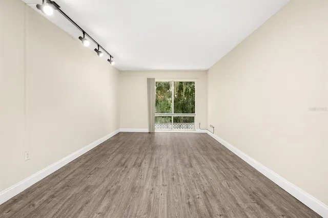 a view of an empty room with wooden floor and fan