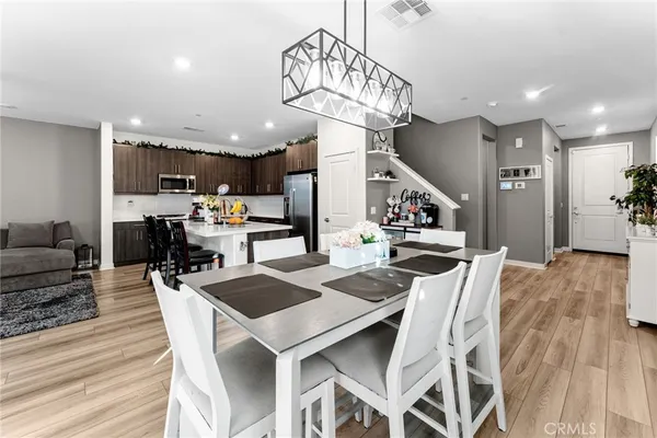 a kitchen with stainless steel appliances a dining table chairs refrigerator and microwave