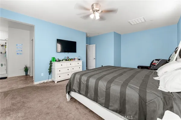 a bedroom with bed a two couches and a flat tv screen
