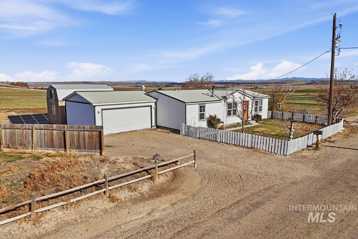 View of front facade featuring driveway, a garage, and a view of rural / pastoral area