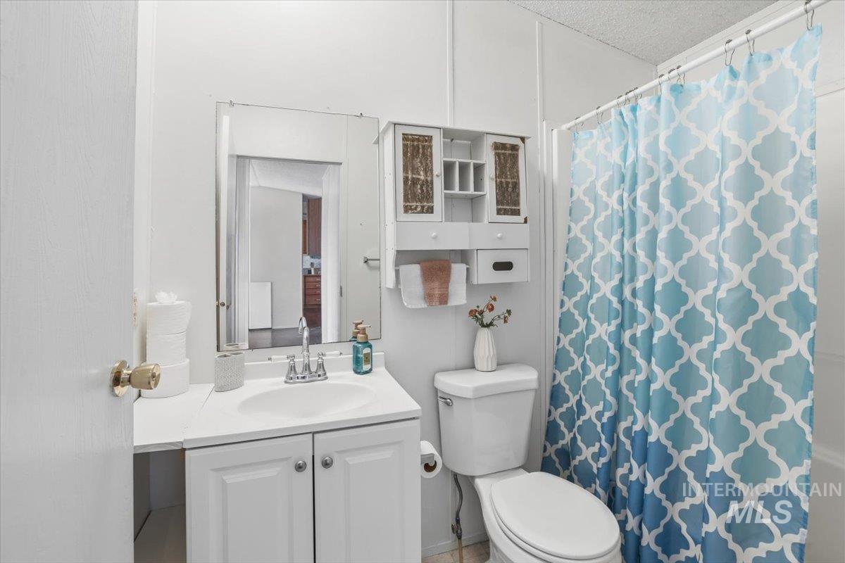 4207 West Pershall Road Marsing, ID 83639 - Photo 18 of 42 Bathroom featuring a shower with shower curtain, vanity, and a textured ceiling