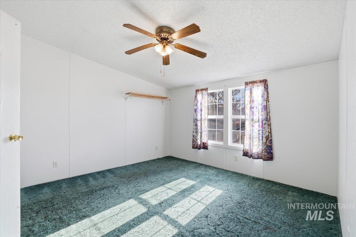 4207 West Pershall Road Marsing, ID 83639 - Photo 25 of 42 Spare room with a textured ceiling, carpet floors, vaulted ceiling, and a ceiling fan