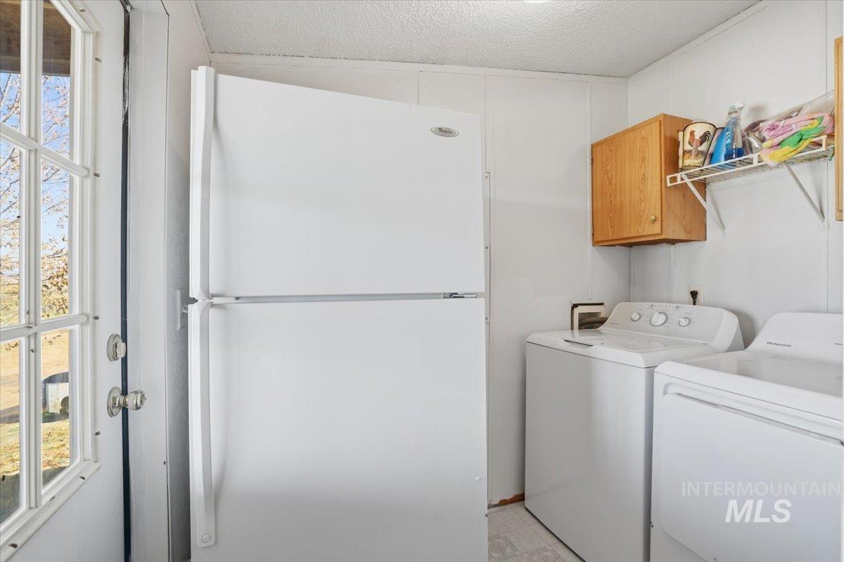4207 West Pershall Road Marsing, ID 83639 - Photo 36 of 42 Washroom with healthy amount of natural light, a textured ceiling, washer and dryer, and cabinet space