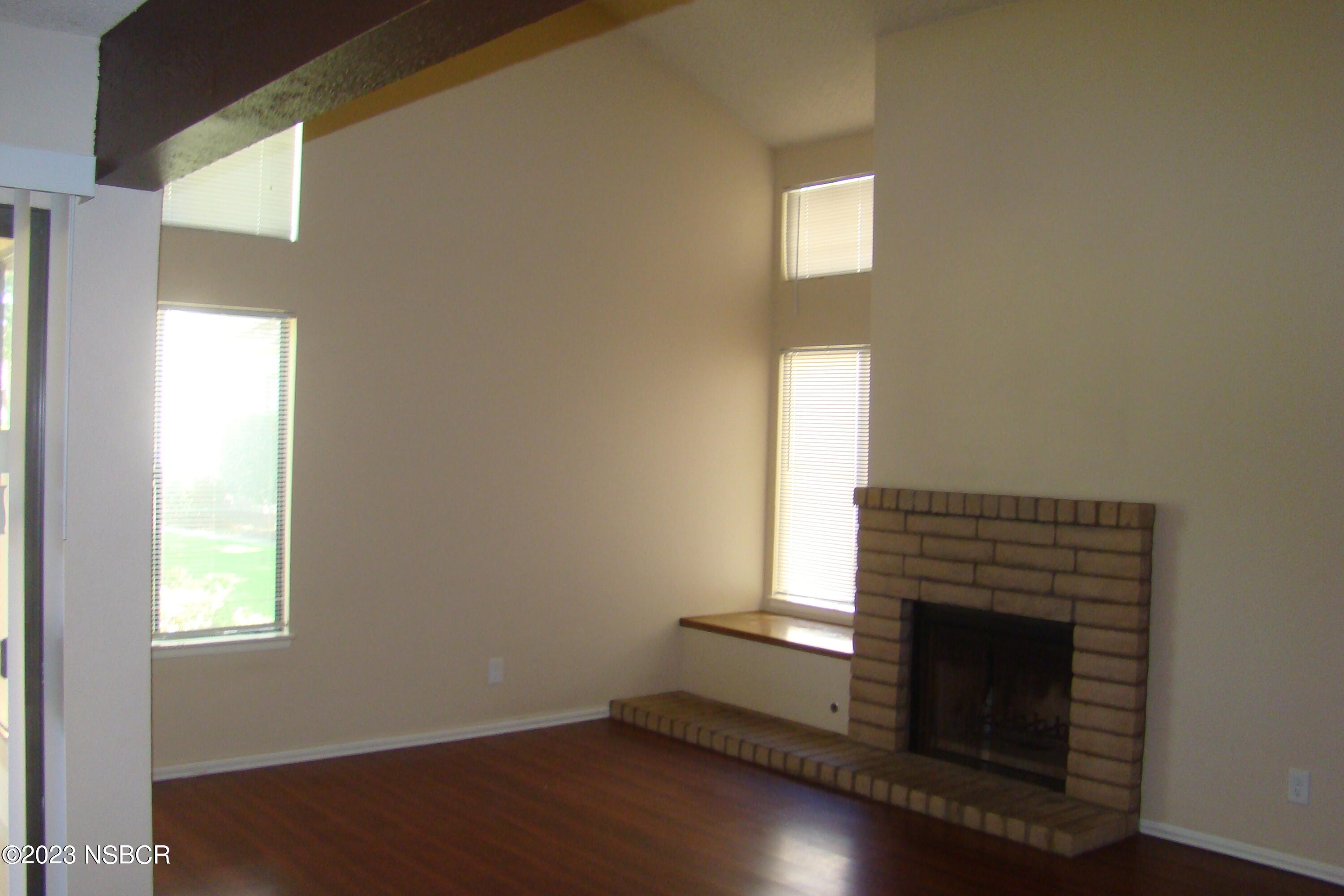 1245 Riverside Drive Lompoc, CA 93436 - Photo 6 of 16 a room with wooden floor a fireplace and windows