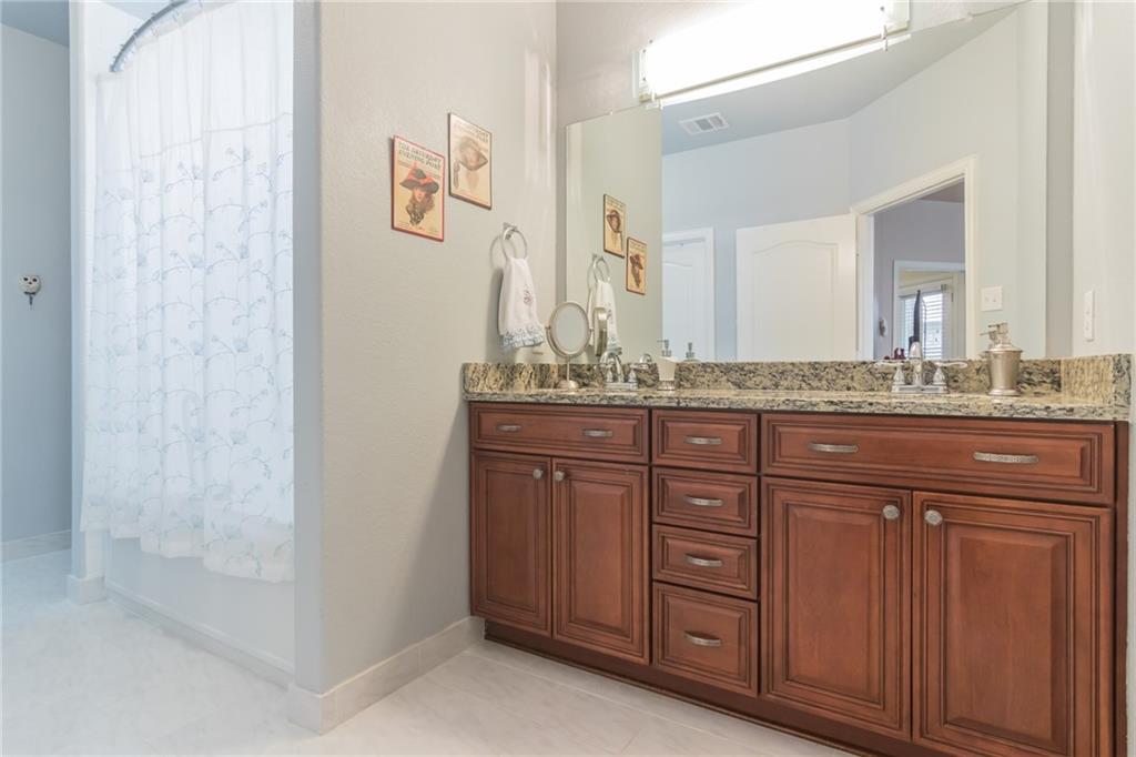 252 Pond View Pass Buda, TX 78610 - Photo 16 of 37 Bathroom featuring double vanity, shower / bath combo with shower curtain, and light tile patterned floors