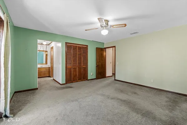 an empty room with closet and a chandelier fan