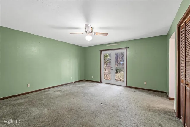 an empty room with chandelier fan and windows